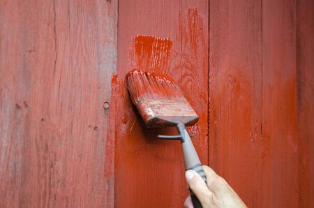 Painting a red plank wall with a paintbrushの写真素材