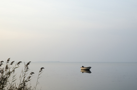 Single rowing boat in calm water a misty morningの写真素材