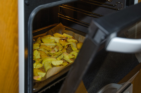 Glance into the oven with sliced roasted potatoesの写真素材