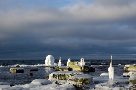 Ice covered fence posts by a rocky coast at the swedish island Oland in the Baltic Seaの写真素材