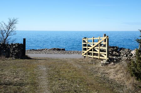 Open traditional wooden farm gate by the coast at the Swedish island Olandの写真素材