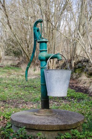 Vintage green hand water pump with a bucketの写真素材