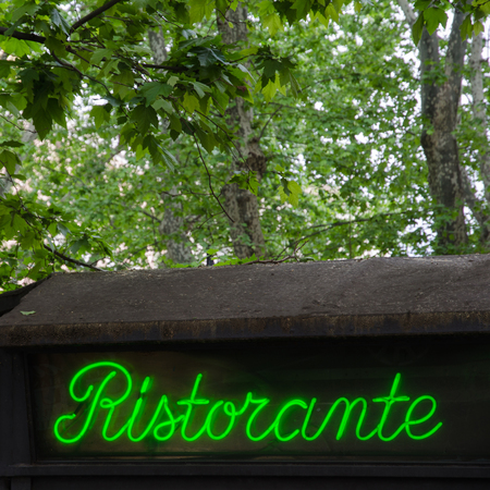Restaurant sign by an old roof and green trees in Rome, Italyの写真素材