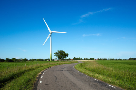 Windmill by a country road side in a green landscapeの写真素材