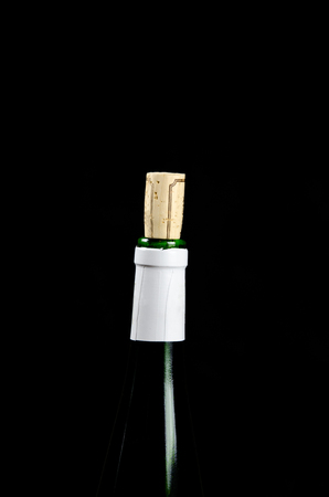 Green wine bottle top with a visible cork at a black backgroundの写真素材