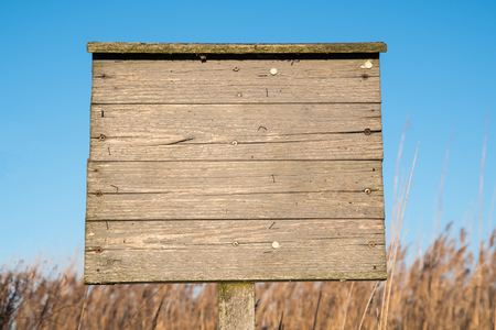 Old weathered wooden blank billboard outdoors by a blue skyの写真素材