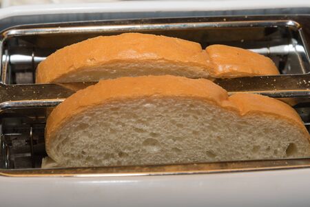 Two fresh white bread slices in a toaster
