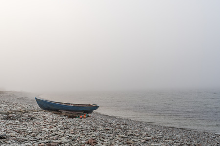 Lone landed rowboat at seaside by a foggy coast at the swedish island Oland in the Baltic Seaの写真素材