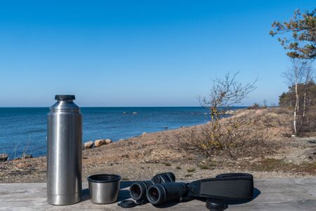 flask and binoculars on a table by the coastの写真素材