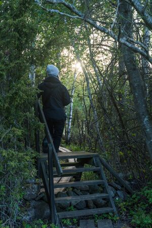 Walking on a stile in  a forest by sunset in a nature reserve with wooden footbridge
