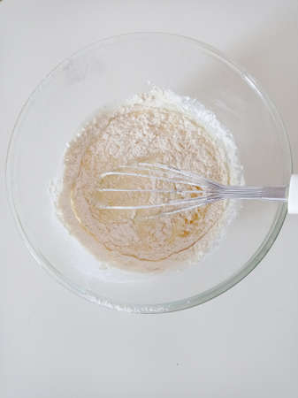 Kneading the dough in a glass mold with a whisk. White background, top viewの写真素材