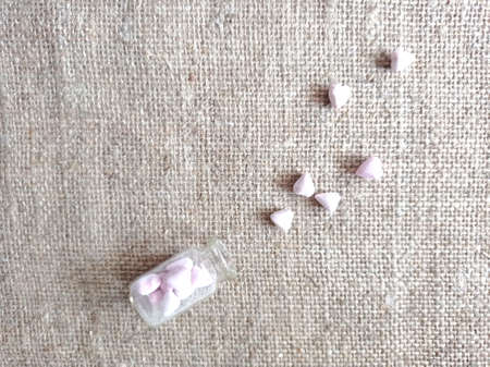 Pink hearts and a glass jar with hearts on a burlap background Small pink hearts figurinesの写真素材