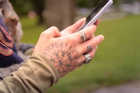 Viking with runes on his hand holding a mobile phoneのeditorial素材