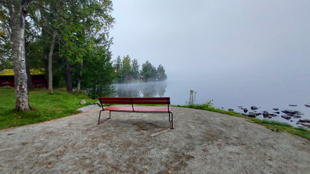 Bench on the shore of the lake in the morning fog.の写真素材