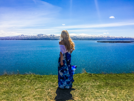 Silhouette of a young girl on the background of a beautiful lake Sevan in Armenia in sunny day