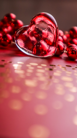 Shining transparent heart and red beads. Perfect Valentine's Day greeting card background. Vertical image in red toneの写真素材