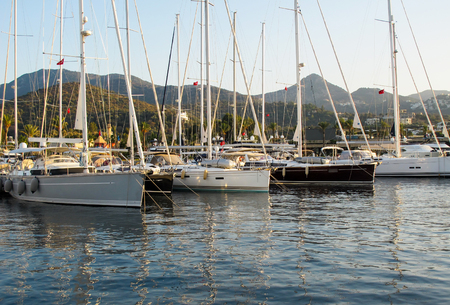 Picturesque marina with sailboats and boats on background of mountains. Yalikavak Turkey. Beautiful reflection in the water of Aegean seaの写真素材