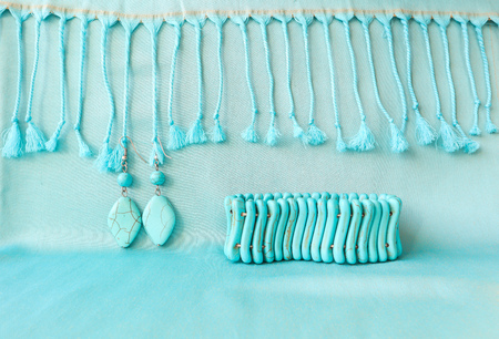 Turquoise bracelet and earrings from natural stone on fringed scarfの写真素材