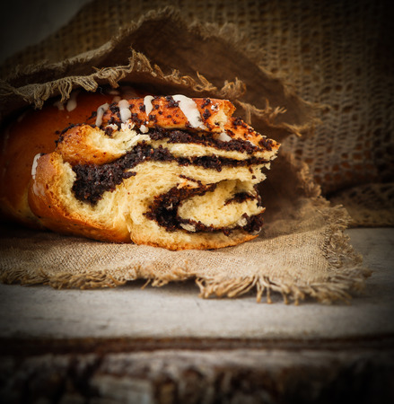 Fresh poppy seed roll on natural linen napkin on rustic wooden backgroundの写真素材