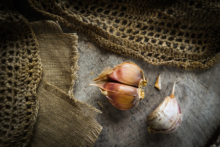 Garlic cloves and natural linen napkin on rustic wooden backgroundの写真素材