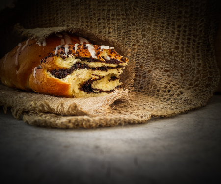 Fresh poppy seed roll on natural linen napkin on rustic wooden backgroundの写真素材