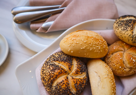 Fresh bread on a white plate with a napkin. Table setting in a restaurantの写真素材