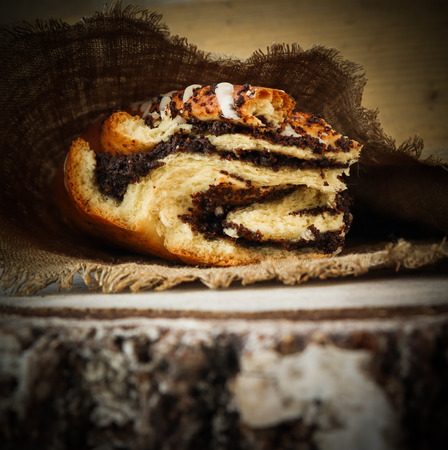 Fresh poppy seed roll on natural linen napkin on rustic wooden backgroundの写真素材