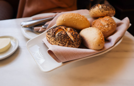 Fresh bread on a white plate with a napkin. Table setting in a restaurantの写真素材