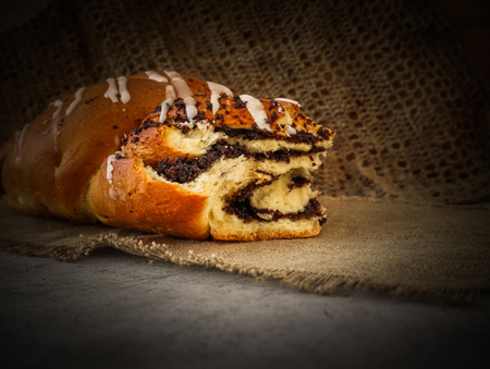 Fresh poppy seed roll on natural linen napkin on rustic wooden backgroundの写真素材