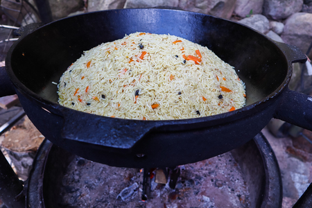 Rice pilaf in a large cast-iron cauldron on fireの写真素材