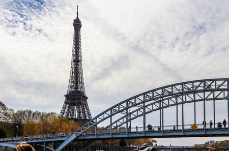 Eiffel Tower against blue sky with clouds and pedestrian bridge Passerelle Debilly over Seine River. Paris France. April 2019のeditorial素材