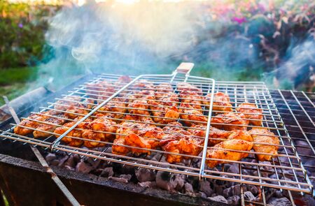 Cooking chicken skewers on the grill in the garden at sunsetの写真素材