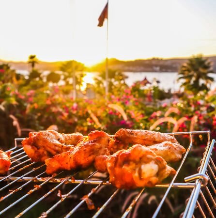 Cooking chicken skewers on the grill in the garden at sunsetの写真素材