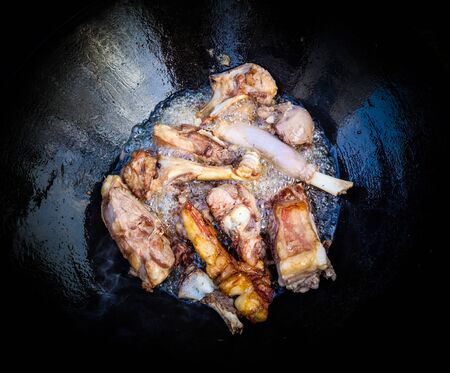 Lamb in a large cast-iron cauldron on fire. Pilaf cooking process.の写真素材