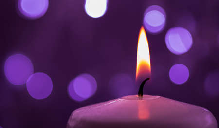 Close up of one burning candle with blurred light backgroundの写真素材