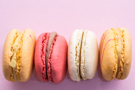 Colorful french cookies macarons set on pink background. Tasty fruit, almond sweet cookies, cake macaron. Holiday backdrop design.の写真素材