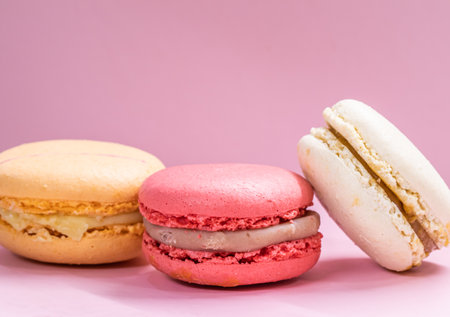 Colorful french cookies macarons set on pink background. Tasty fruit, almond sweet cookies, cake macaron. Holiday backdrop design.の写真素材