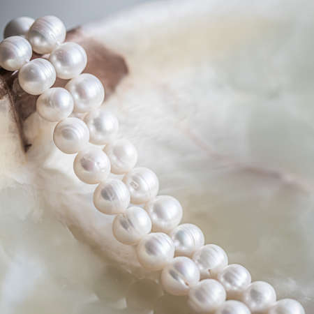 Nature white string of pearls on marble background in soft focus, with highlights.の写真素材