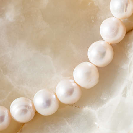 Nature white string of pearls on marble background in soft focus, with highlights.の写真素材