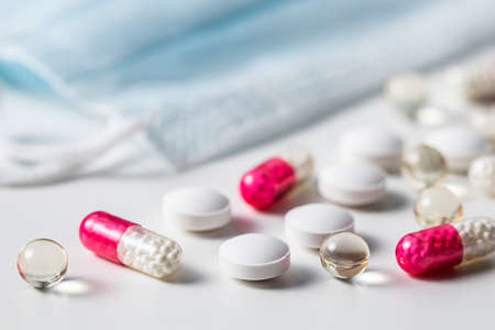 Red capsules, pills and medical masks on a white background. Health care, medical, pharmacy and illness conceptの写真素材