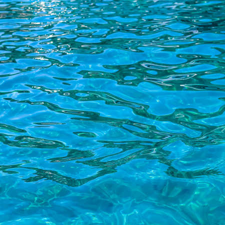 Turquoise sea waves in sunshine glow as surface background. Summer holidays and coastal nature conceptの写真素材