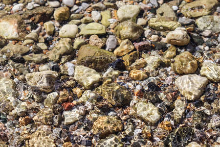 Background from stones and flowing waves on the sea beach. Summer holidays and coastal nature conceptの写真素材