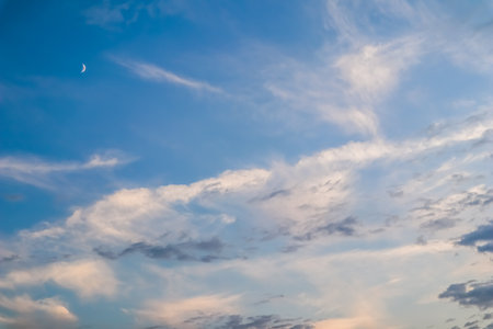 Blue sky background with white and pink clouds and moon at sunsetの写真素材