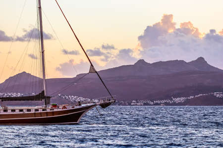 Beautiful sunset on the Aegean Sea with mountains and a sailboat. Seascape, travel and nature...