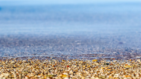 A background of sand, small pebbles and flowing wave on the sea beach. Summer vacation and coastal nature conceptの写真素材