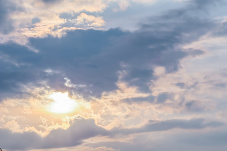 Cloudy sky background with sunlight through clouds at sunsetの写真素材