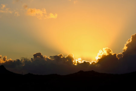A spectacular sunset or sunrise scene with intense golden crepuscular rays bursting from behind...