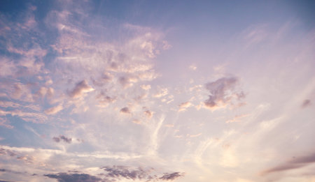 Beautiful sunset sky with delicate wispy clouds in soft pastel colors of pink, purple, and blue....
