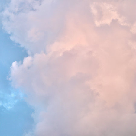 A serene sky scene featuring a patchwork of soft blue, pale pink, and gray cumulus clouds,...