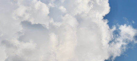 A massive, dense formation of bright white and gray cumulonimbus clouds filling the frame, with a small patch of blue sky visible. High quality photoの写真素材